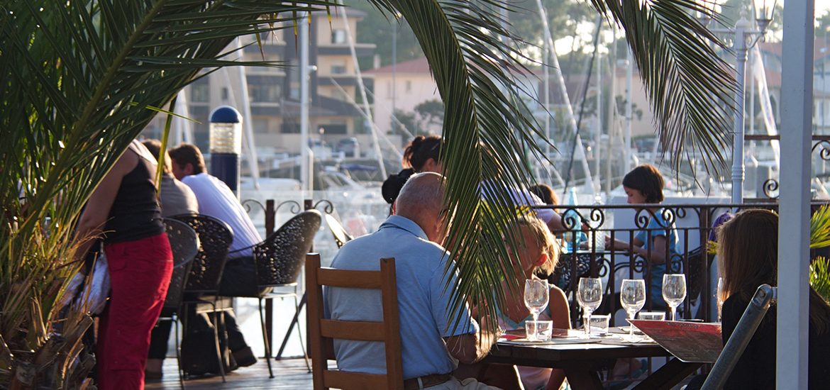 Personnes sur la terrasse d'un restaurant avec une vue sur un port
