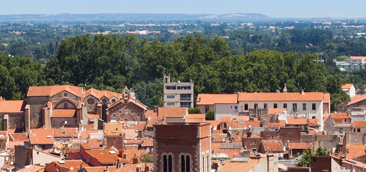 Vue aérienne de la vieille ville de Perpignan avec des toits en tuiles et le clocher d'une église.